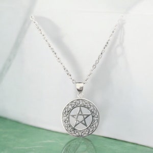 May include: A silver necklace with a circular pendant featuring a pentagram inside a Celtic knot design.