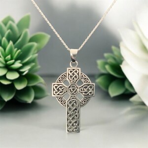 May include: A silver Celtic knot cross pendant necklace. The cross is intricately designed with a knot pattern and hangs from a silver chain.