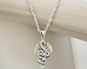 May include: A silver necklace with a dragon pendant. The dragon is coiled with its wings spread out.