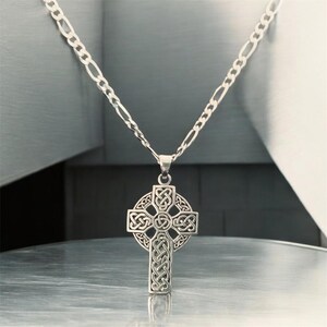 May include: A silver chain necklace with a Celtic cross pendant. The cross is intricately designed with knots and is a popular symbol of Irish heritage.
