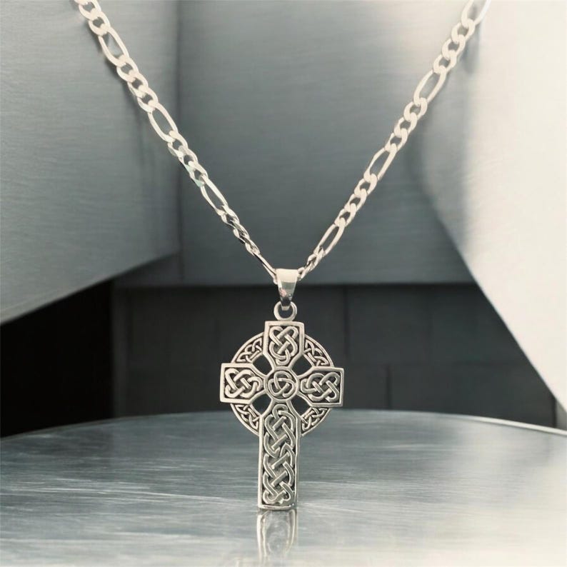May include: A silver chain necklace with a Celtic cross pendant. The cross is intricately designed with knots and is a popular symbol of Irish heritage.