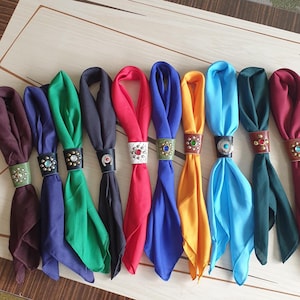 Op de afbeelding: Tien kleurrijke bandana's met leren en juwelen accenten. De bandana's zijn in een rij gerangschikt, met de bruine bandana links en de donkerrode bandana rechts.