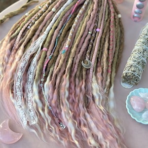 May include: A set of long, wavy, synthetic dreadlocks in shades of brown, pink, and blonde. The dreadlocks are decorated with beads, lace, and charms.