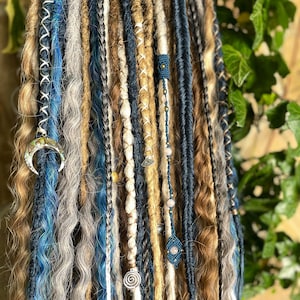 May include: A collection of handmade dreadlocks in various shades of blue, brown, and gray. Some dreads are adorned with decorative beads, charms, and intricate stitching. The dreadlocks are styled with a mix of textures and lengths, creating a bohemian aesthetic.