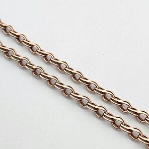 Op de afbeelding: Een close-up van een ketting van roségoud. De ketting is gemaakt van kleine, ovale schakels.
