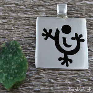 May include: A silver pendant with a black stylized figure of a person with outstretched arms and a circle on its head.