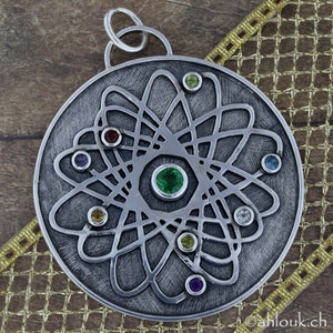 May include: A silver pendant with a detailed atom design and colorful gemstones. The pendant is round and has a loop at the top for attaching a chain.