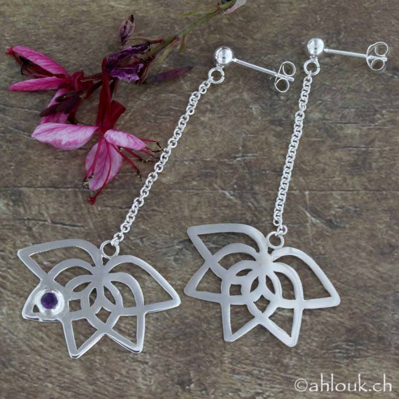 May include: A pair of silver dangle earrings with a delicate chain and a floral design. Each earring features a small purple gemstone in the center of the flower.