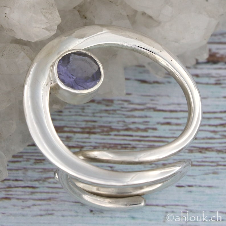 May include: A silver ring with a swirling design and a purple gemstone in the center.