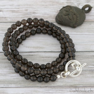 May include: A triple-strand necklace made of dark brown smoky quartz beads with a silver toggle clasp.