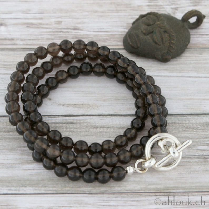 May include: A triple-strand necklace made of dark brown smoky quartz beads with a silver toggle clasp.