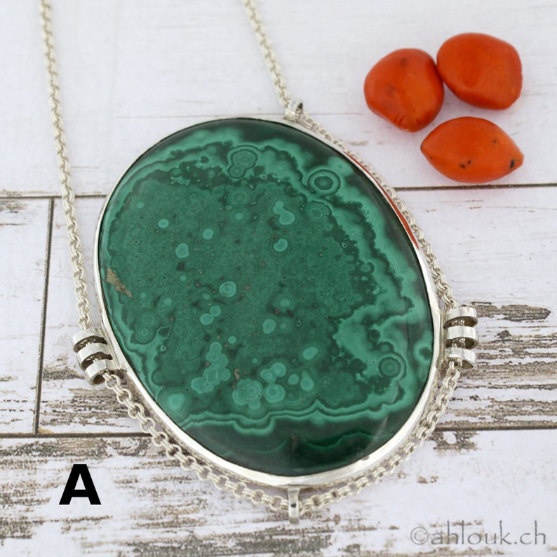Puede incluir: Un collar de cadena de plata con un gran colgante ovalado de malaquita verde. El colgante tiene un patr&oacute;n de remolino de verde y blanco.