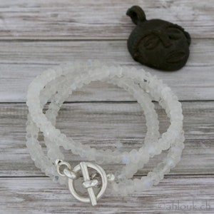 May include: A white moonstone beaded necklace with a silver toggle clasp. The necklace is layered and has a delicate, feminine look.