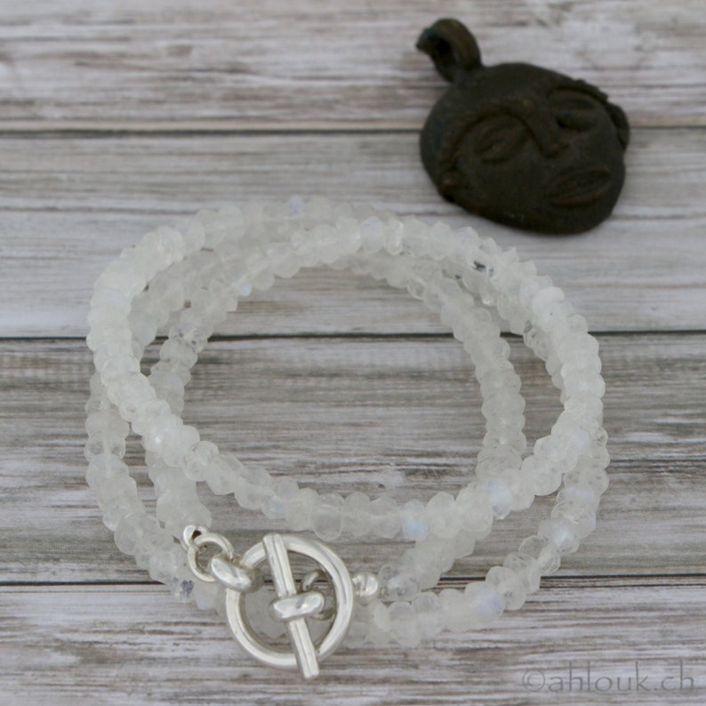 May include: A white moonstone beaded necklace with a silver toggle clasp. The necklace is layered and has a delicate, feminine look.