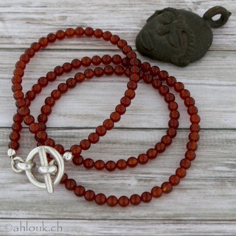 May include: A double strand necklace made of carnelian beads with a silver toggle clasp.