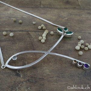May include: A silver necklace with a fish pendant and a green leaf design. The pendant is adorned with small gemstones in various colors.