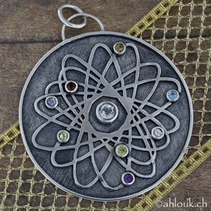 May include: A silver pendant with a detailed atom design and colorful gemstones. The pendant is round and has a textured surface.