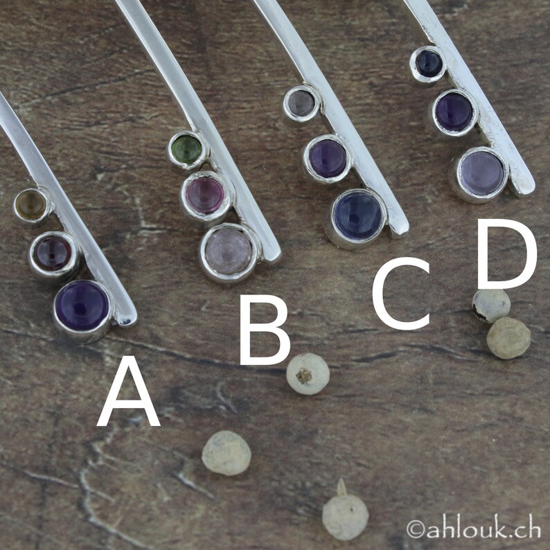 May include: Five silver bar pendants with different colored gemstones. The pendants are labeled A, B, C, and D. The gemstones are purple, green, pink, and clear.