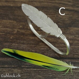 May include: Silver feather ring with a double band design. The ring is open on both sides and can be worn on multiple fingers.