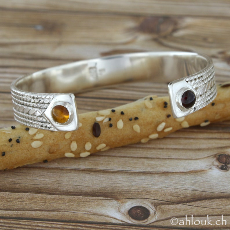 Puede incluir: Pulsera de plata con un dise&ntilde;o texturizado y dos acentos de piedras preciosas. Una piedra es &aacute;mbar y la otra es granate.