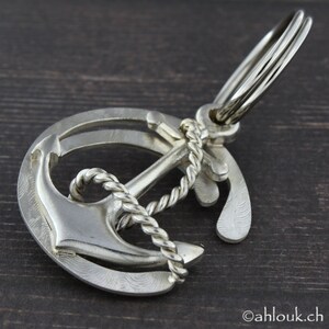 May include: Silver anchor keychain with a rope design. The anchor is attached to a silver ring with a key ring.