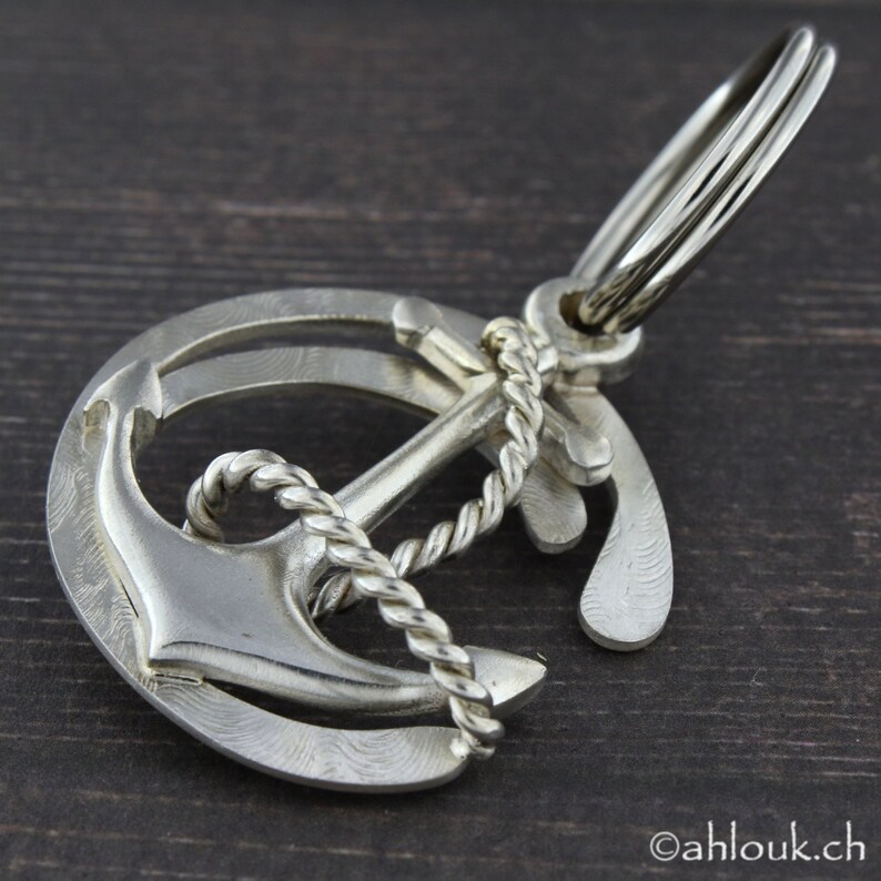 May include: Silver anchor keychain with a rope design. The anchor is attached to a silver ring with a key ring.