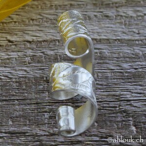 May include: A silver ring with a textured, swirling design. The ring is made of metal and has a unique, organic shape.