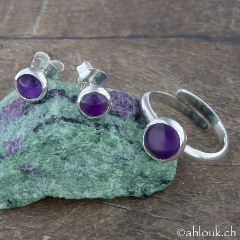 May include: A set of sterling silver jewelry featuring amethyst gemstones. The set includes a ring and a pair of earrings.