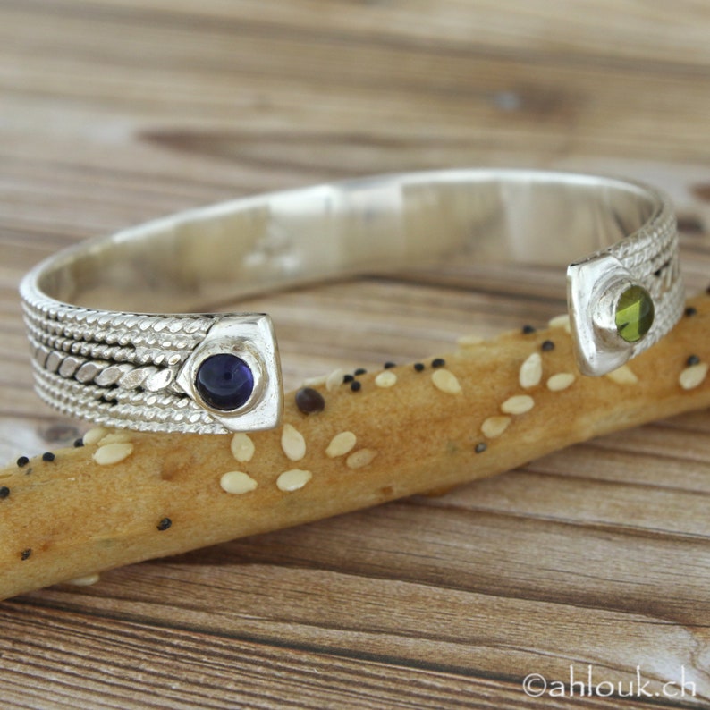 Puede incluir: Pulsera de plata con dise&ntilde;o trenzado y dos acentos de piedras preciosas. Una piedra preciosa es de color morado oscuro y la otra es de color verde claro.