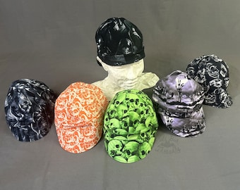 May include: Six different welding caps with skull and skeleton designs. The caps are in various colors, including black, white, orange, green, and purple. The caps are made of a soft, comfortable fabric and are perfect for protecting your head and hair from sparks and heat.