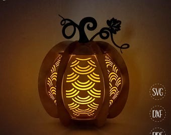 May include: A lit-up, wooden pumpkin lantern with a decorative cutout design. The pumpkin has a stem and vine detail at the top. The text "Biberwerke" is in the upper left corner. The lantern is lit from within, creating a warm glow.