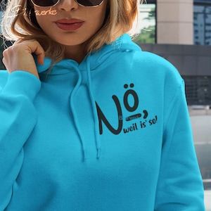 Könnte beinhalten: Ein türkisblauer Hoodie mit einem schwarzen Aufdruck, der "Nö, weil is' so!" sagt.