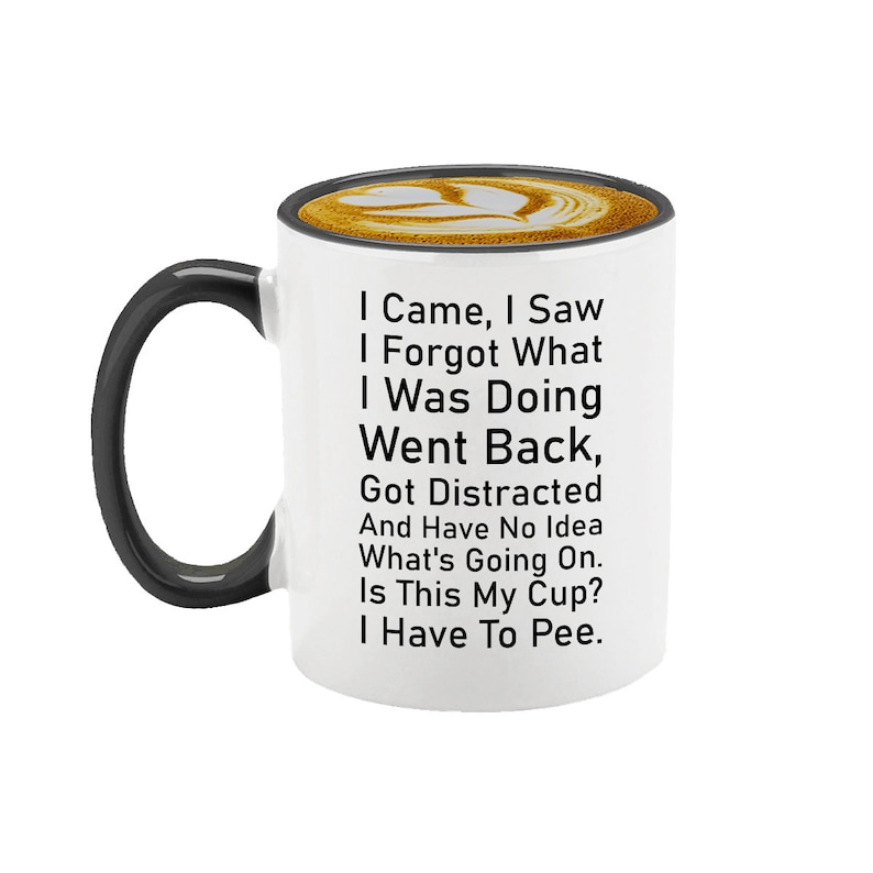 May include: White ceramic coffee mug with a black handle. The mug has a black rim and a humorous saying printed on it: "I Came, I Saw, I Forgot What I Was Doing, Went Back, Got Distracted And Have No Idea What's Going On. Is This My Cup? I Have To Pee."