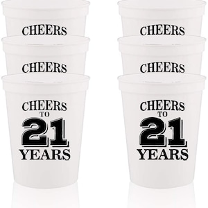 May include: Set of six white plastic cups with black text. The cups say "Cheers to 21 Years".