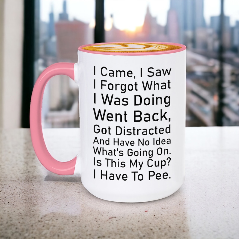 May include: White ceramic coffee mug with a pink rim and handle. The mug has black text that reads: "I Came, I Saw, I Forgot What I Was Doing, Went Back, Got Distracted And Have No Idea What's Going On. Is This My Cup? I Have To Pee."