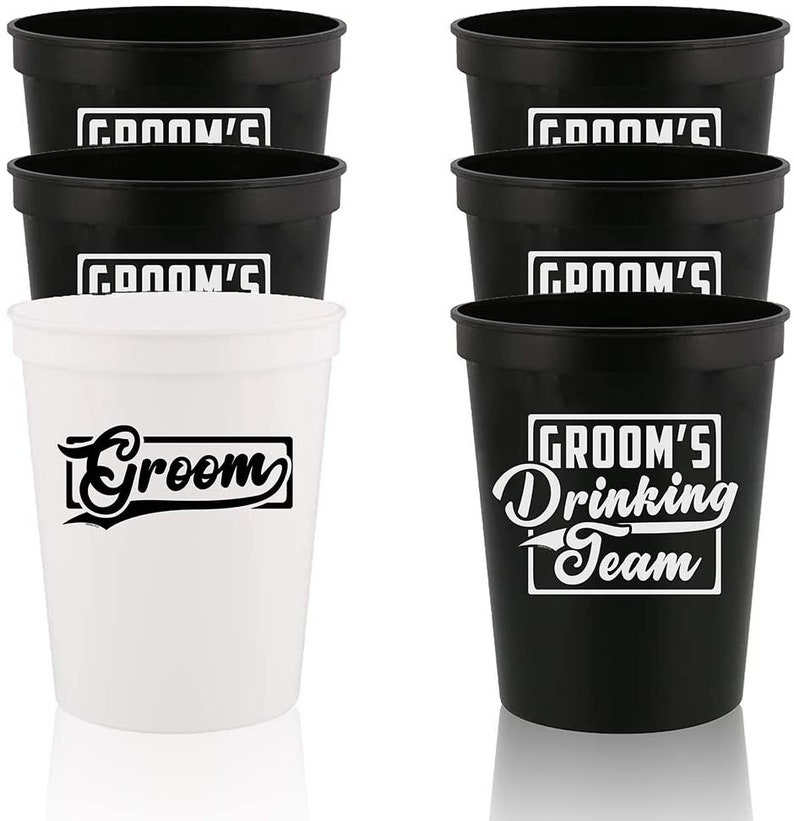 May include: Set of 6 black and white plastic cups. The black cups have the text "Groom's Drinking Team" in white. The white cups have the text "Groom" in black.