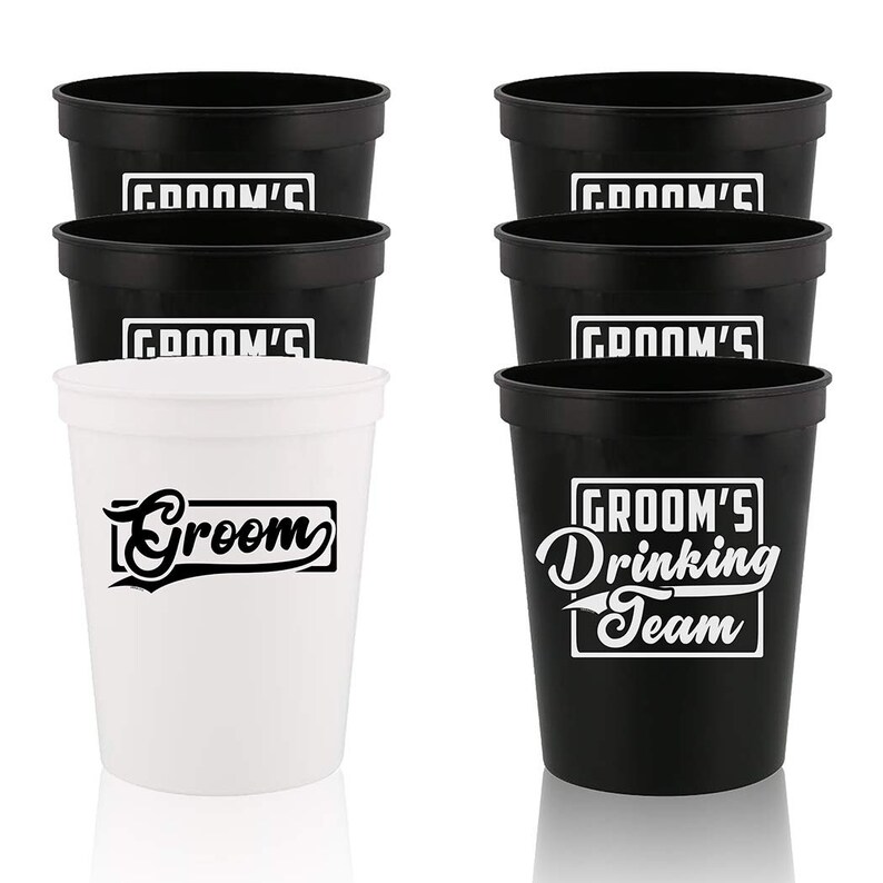 May include: Set of six black and white plastic cups.  Four cups have the text "Groom's" printed on them. One cup has the text "Groom" printed on it. One cup has the text "Groom's Drinking Team" printed on it.