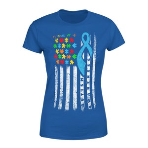 May include: A blue t-shirt with a distressed American flag design. The flag features puzzle pieces in various colors and a light blue ribbon with the words "AUTISM AWARENESS". The shirt is a crew neck style.