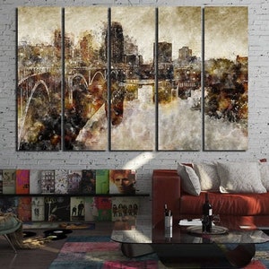 May include: A multi-panel canvas art print depicting a cityscape with a bridge and buildings, rendered in muted tones of brown, beige, and gray. The artwork is displayed on a white brick wall, with a modern living room setting.