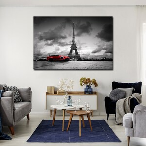 Puede incluir: Una fotograf&iacute;a en blanco y negro de la Torre Eiffel en Par&iacute;s, Francia. Un coche rojo vintage est&aacute; aparcado en primer plano. El cielo est&aacute; nublado.