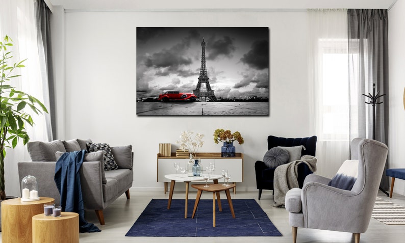 Puede incluir: Una fotograf&iacute;a en blanco y negro de la Torre Eiffel en Par&iacute;s, Francia. Un coche rojo vintage est&aacute; aparcado en primer plano. El cielo est&aacute; nublado.