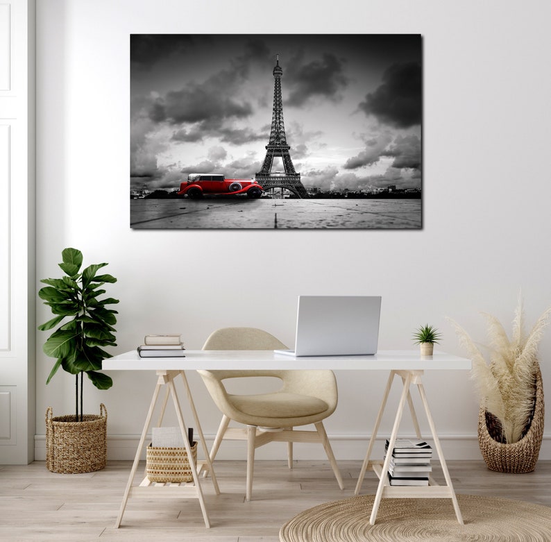Puede incluir: Una fotograf&iacute;a en blanco y negro de la Torre Eiffel en Par&iacute;s, Francia. Un coche rojo vintage est&aacute; aparcado en primer plano. El cielo est&aacute; nublado.