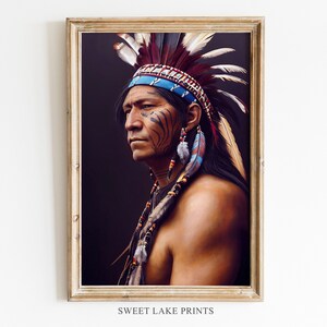 May include: A framed print featuring a portrait of a Native American man. He wears a feathered headdress with blue and red accents, face paint, and beaded earrings. The artwork has a dark background and is framed in a gold-colored frame. The text "SWEET LAKE PRINTS" is at the bottom.