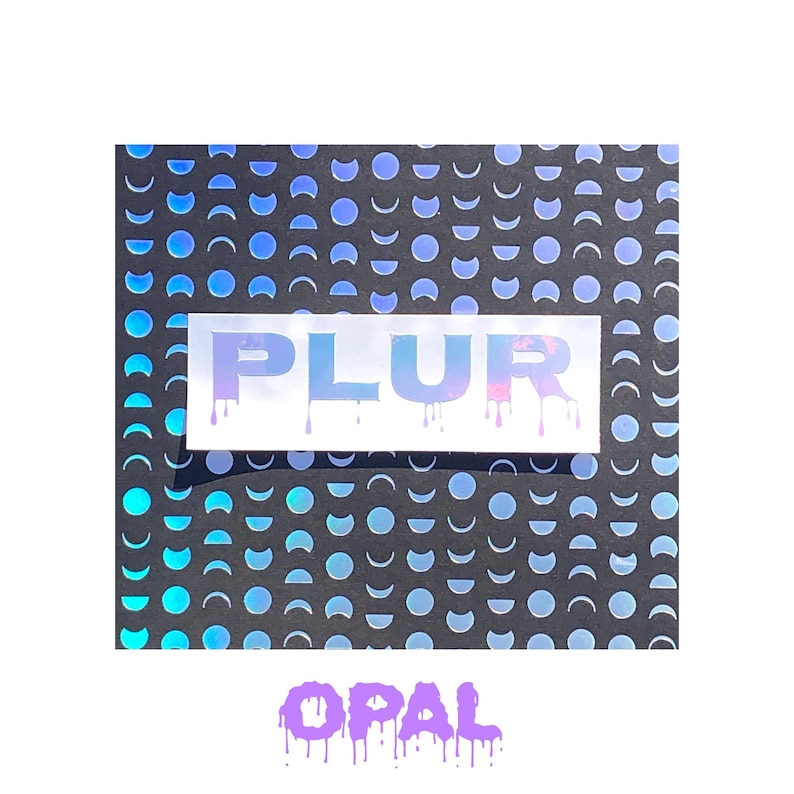 May include: A white sticker with the word "PLUR" in iridescent letters with a dripping effect. The sticker is on a black background with a pattern of blue crescent moons.
