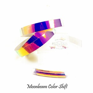 May include: A roll of iridescent holographic tape in shades of pink, purple, and gold. The tape is labelled "Moonbeam Color Shift".