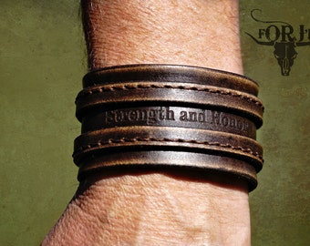 May include: A brown leather bracelet with the words "Strength and Honor" embossed on it.