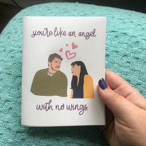 May include: A card with a cartoon illustration of a couple with the text "you're like an angel with no wings."