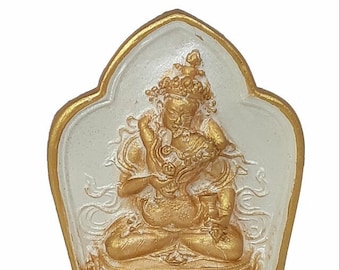 May include: A white and gold statue of a deity sitting in a meditative pose. The statue is in a heart-shaped frame with intricate details.