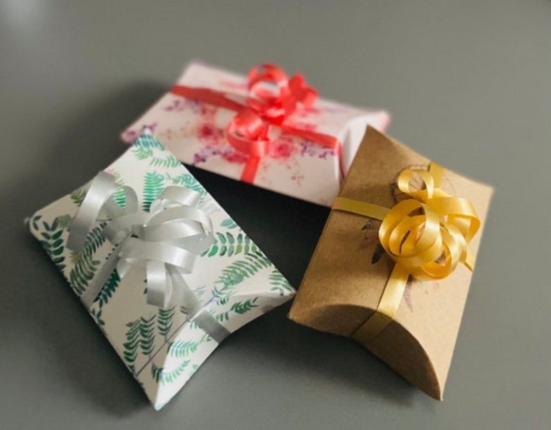 May include: Three gift boxes with different patterns and colors. The boxes are tied with ribbons in silver, gold, and red.