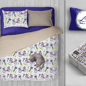 May include: A white bedding set featuring a lavender and bicycle design. The set includes a duvet cover, two pillowcases, and a decorative pillow with the word "Love" in a wreath of lavender.